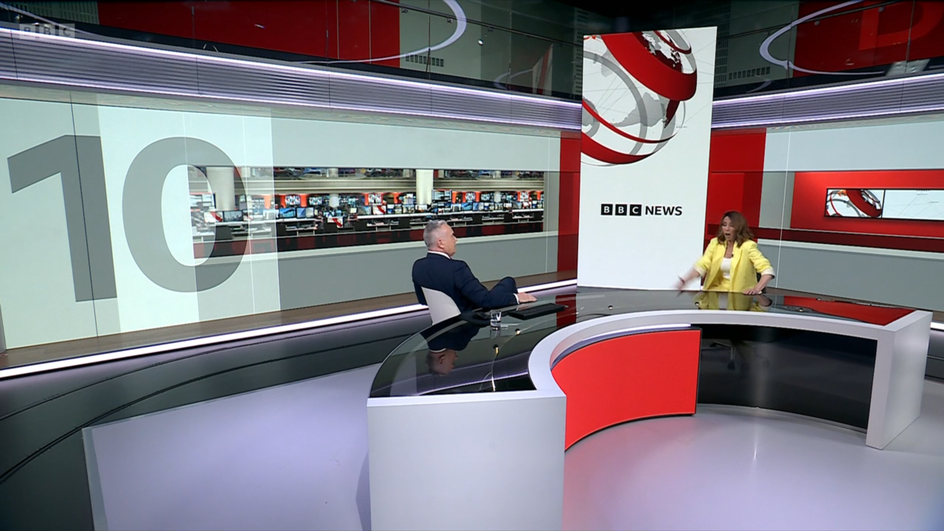 The new curved BBC News desk, similar to the one used for Politics Live at BBC Millbank. A tall screen sits between Huw Edwards and Alex Jones